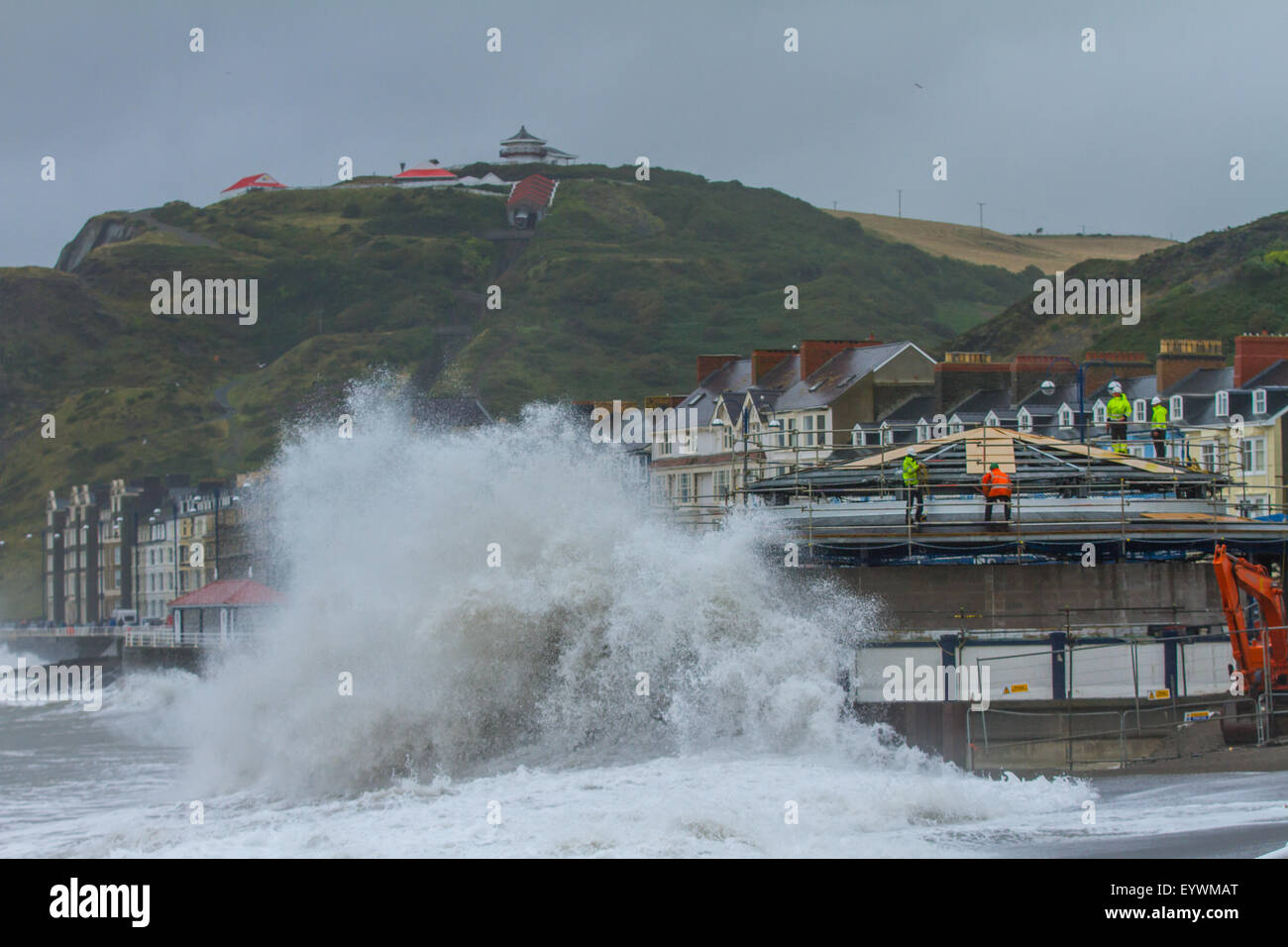 Aberystwyth, Wales, Regno Unito. Il 4 agosto 2015. Le tempeste. Un 5-8 piedi si gonfiano, venti alti e un alta marea cmbine per ancorare Aberystwyth mare con onde enormi, come operai a proseguire i lavori sul lungomare di rivalorizzare bandstand Credito: Alan Hale/Alamy Live News Foto Stock