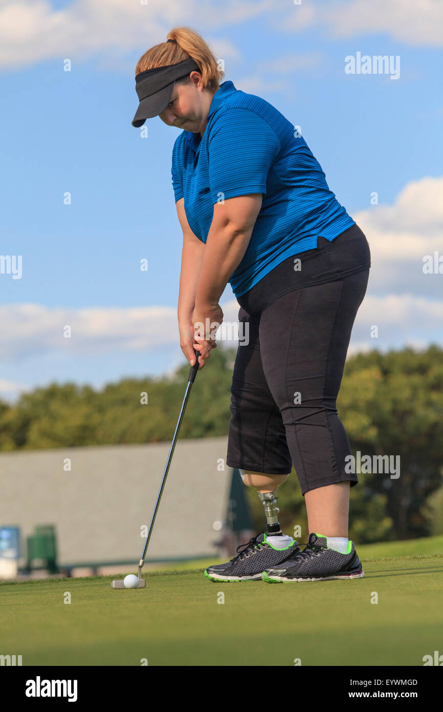 Donna con gamba protesico al putting green da golf Foto Stock