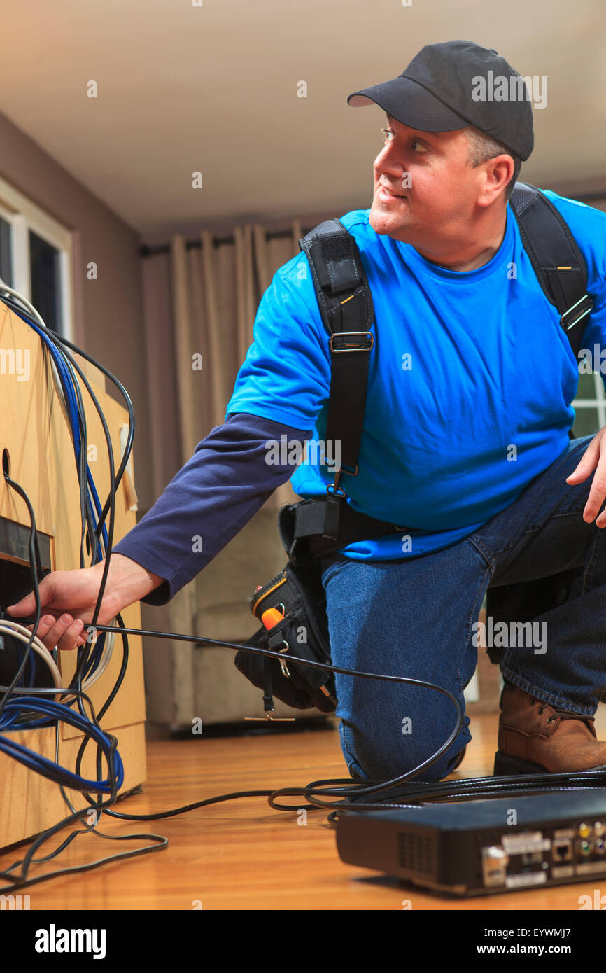 Cavo installer funzionante in una casa dietro il televisore Foto Stock