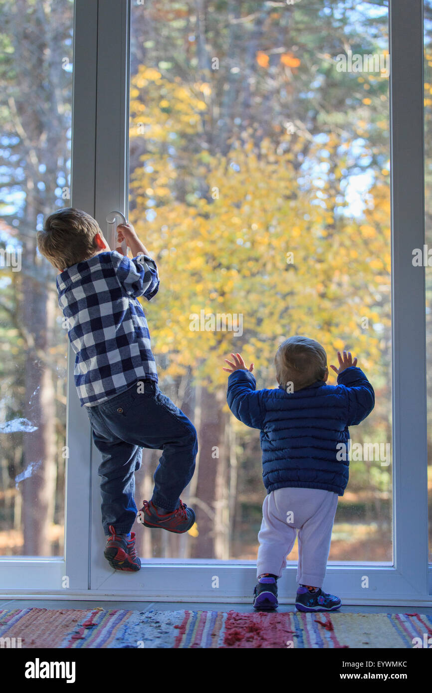 Vista posteriore di un fratello e sua sorella baby arrampicata fuori della porta Foto Stock