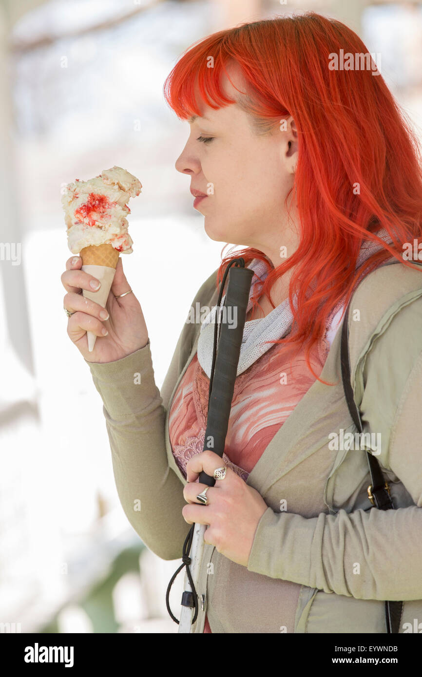 Giovane donna cieca con la sua canna da zucchero godendo di gelato Foto Stock