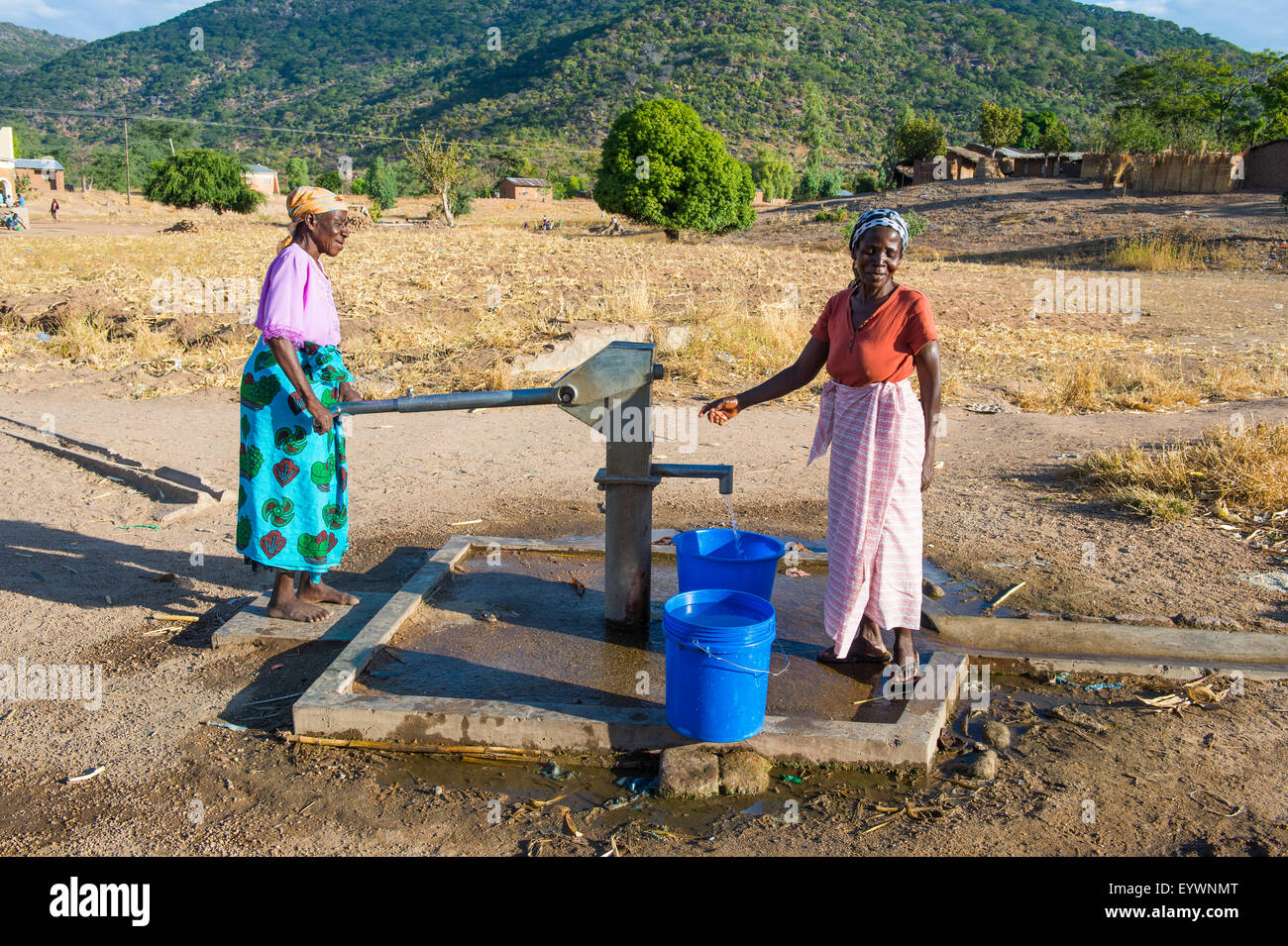 Le donne il pompaggio di acqua al di fuori di un bene al Lago Malawi, Cape Maclear, Malawi, Africa Foto Stock