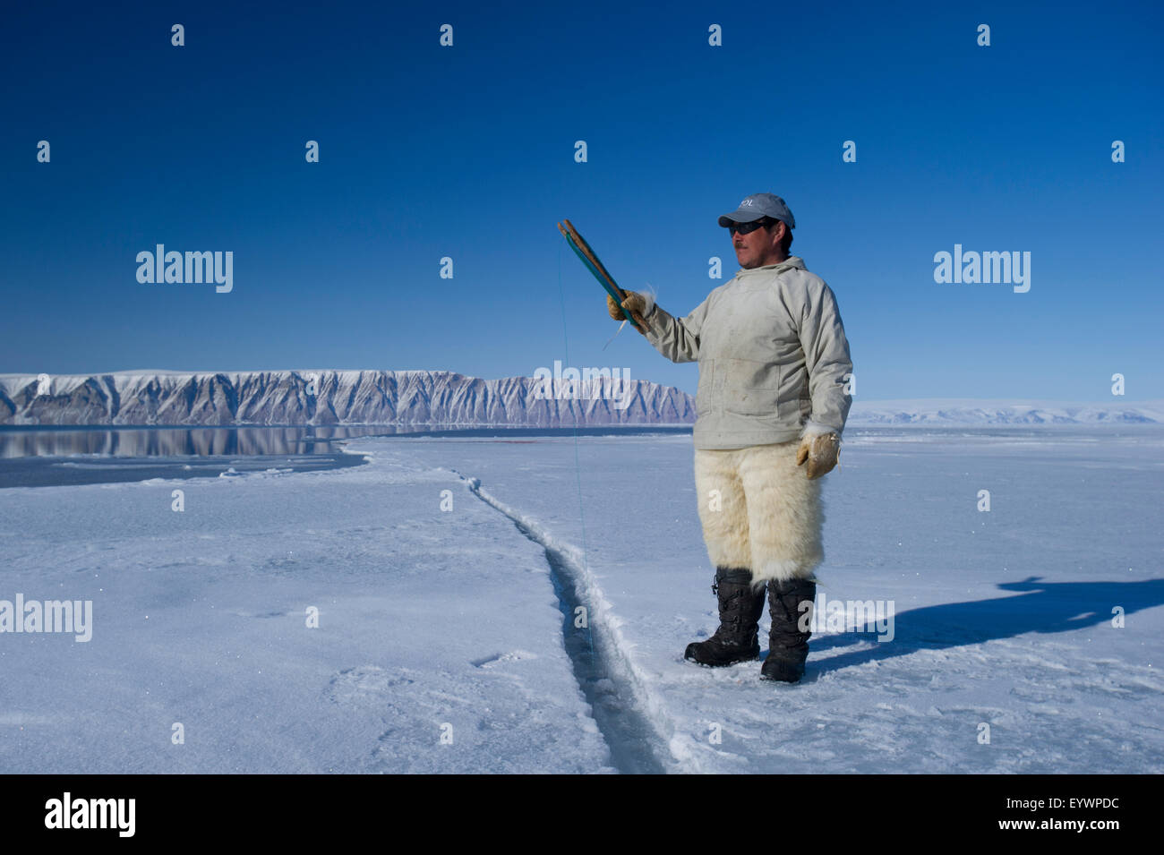 Cacciatori Inuit filo da pesca a bordo floe per merluzzo artico, sculpin e halibut vicino isola Herbert, Groenlandia, Danimarca Foto Stock