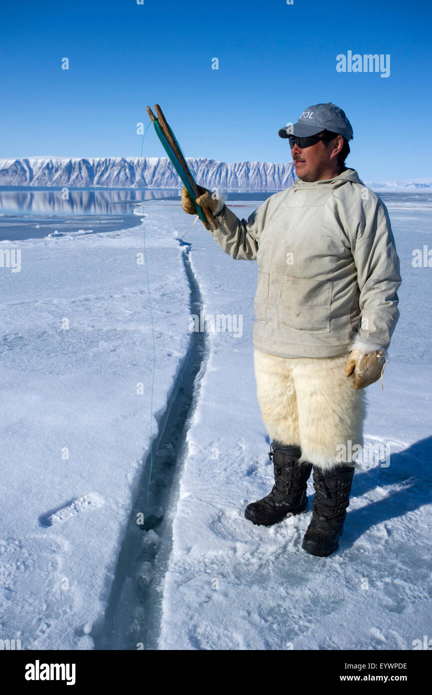 Cacciatori Inuit filo da pesca a bordo floe per merluzzo artico, sculpin e halibut vicino isola Herbert, Groenlandia, Danimarca Foto Stock