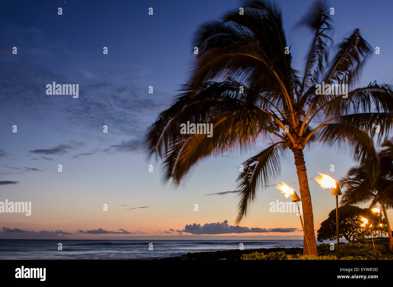 Torce Tiki al tramonto sulla spiaggia di Poipu Beach, Kauai, Hawaii, Stati Uniti d'America, il Pacifico Foto Stock