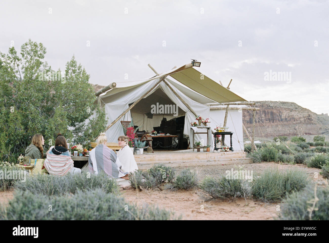 Il gruppo di donne amici gustando un pasto all'aperto in un deserto da una grande tenda. Foto Stock