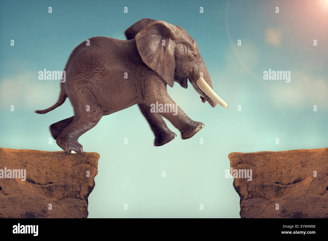 Salto di fede concetto elephant di saltare attraverso un crepaccio Foto Stock