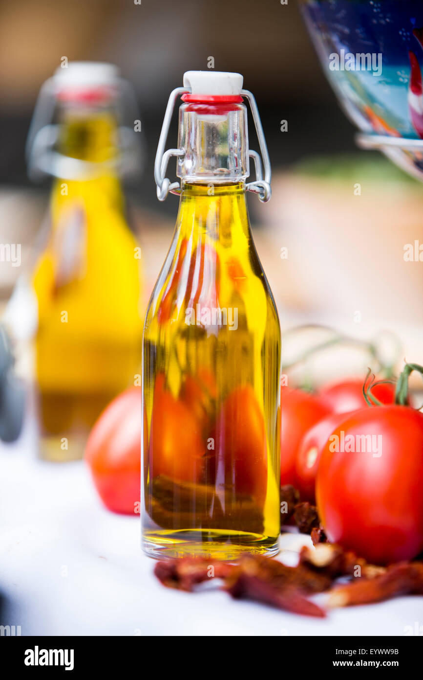 Bottiglia di olio di oliva con pomodori e peperoncino. Foto Stock