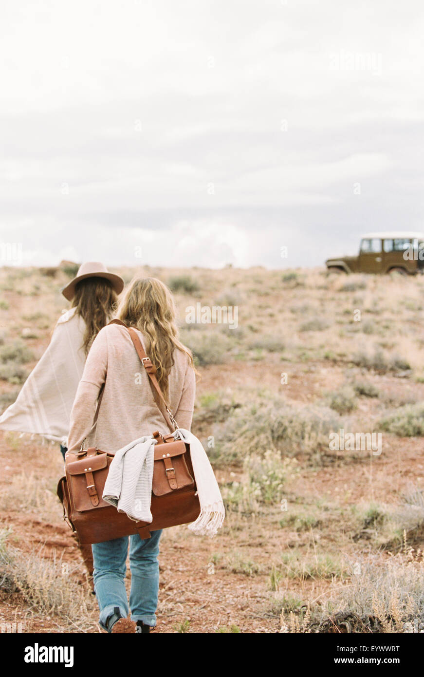 Due donne in cammino verso 4x4 parcheggiata in un deserto. Foto Stock