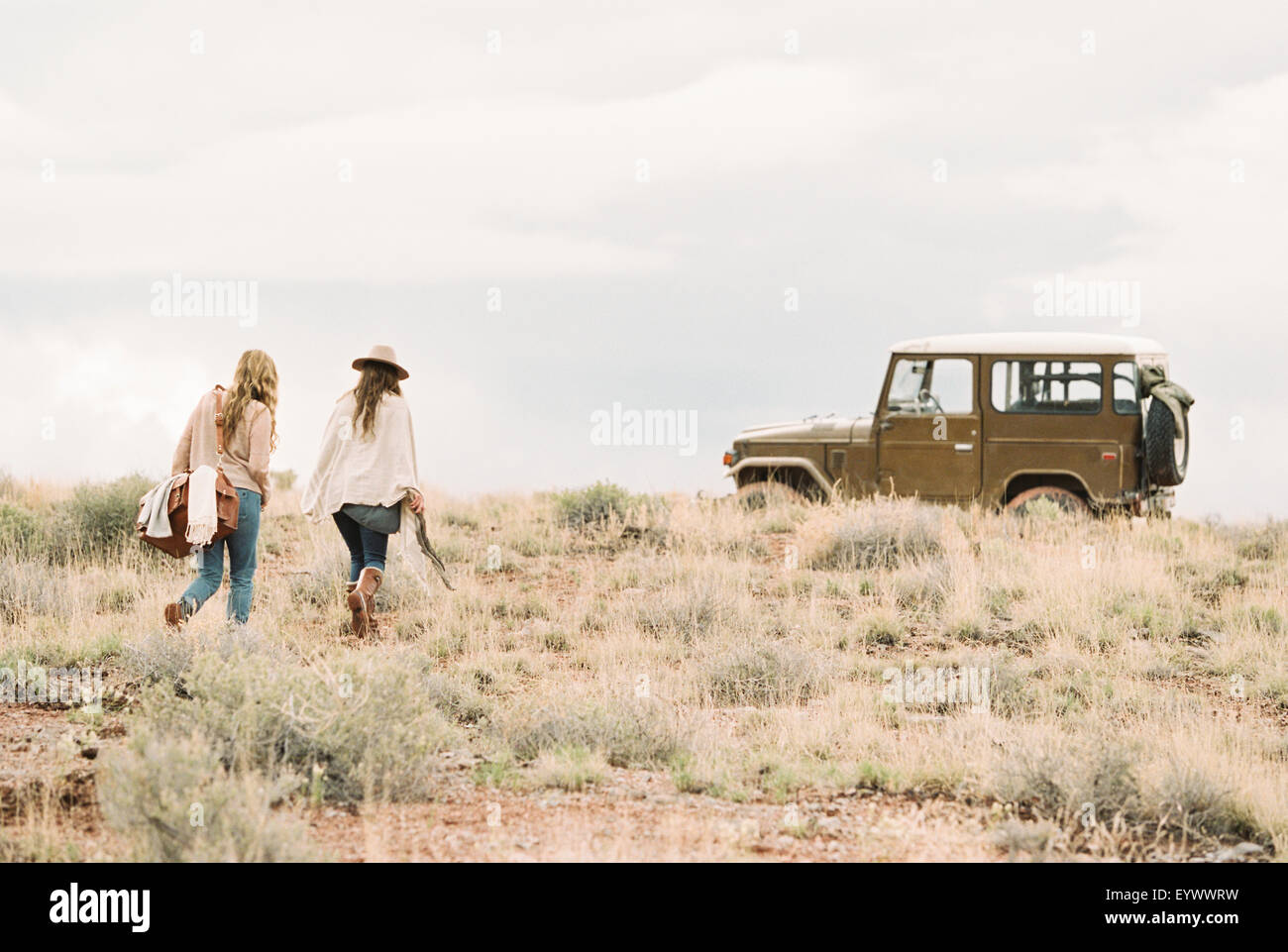 Due donne in cammino verso 4x4 parcheggiata in un deserto. Foto Stock