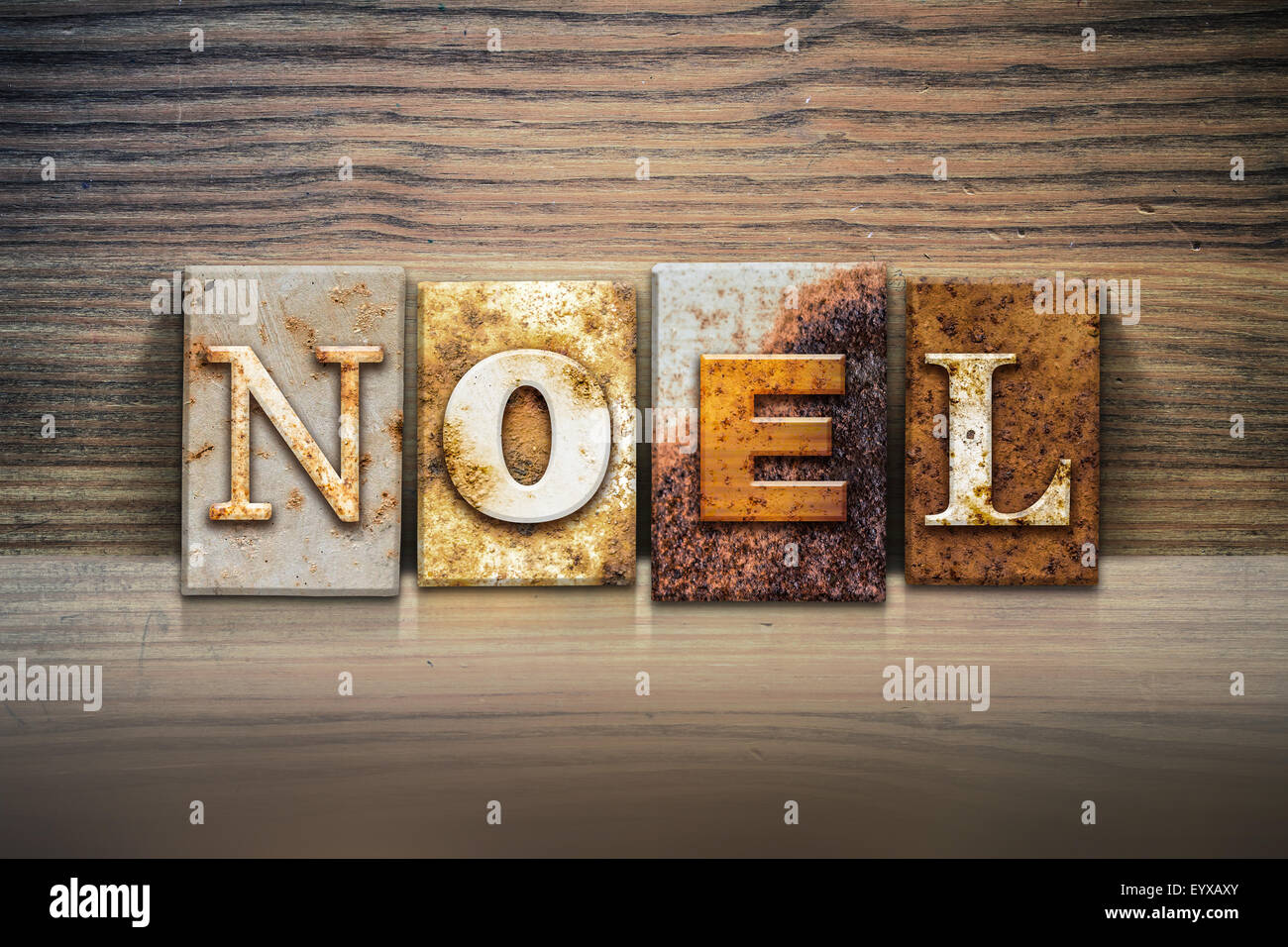 La parola 'NOEL' scritto in metallo arrugginito rilievografia tipo seduto su un listello di legno dello sfondo. Foto Stock