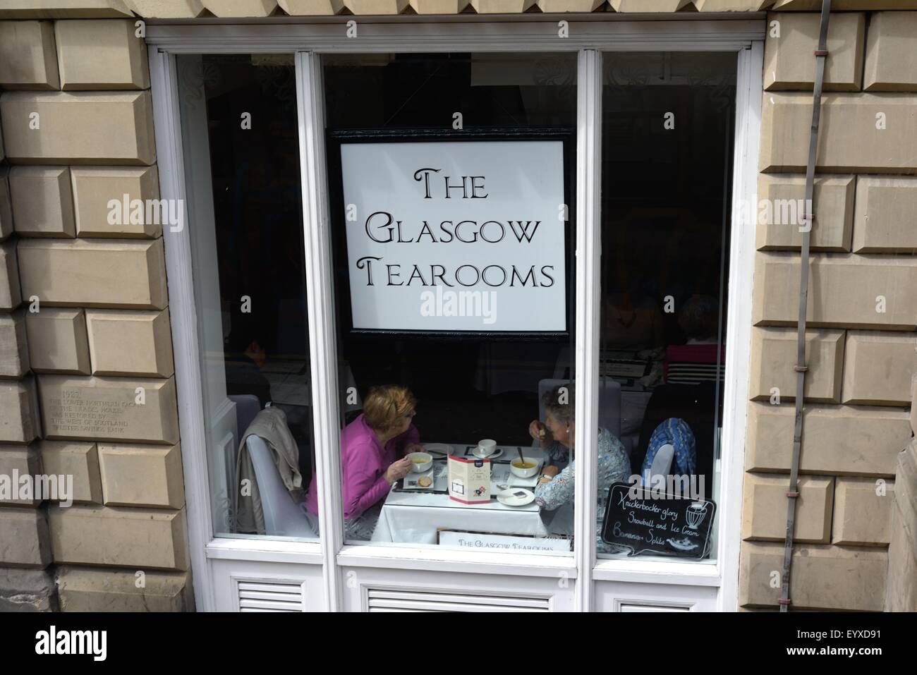 Signore senior che chiacchierano con tè e torte nella finestra del tearooms, Glasgow Foto Stock
