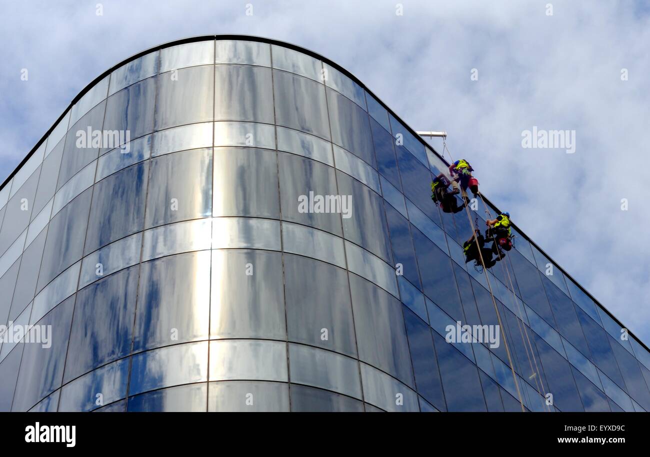I lavavetri sono sospesi in alto su un moderno blocco di uffici in vetro a Glasgow Foto Stock