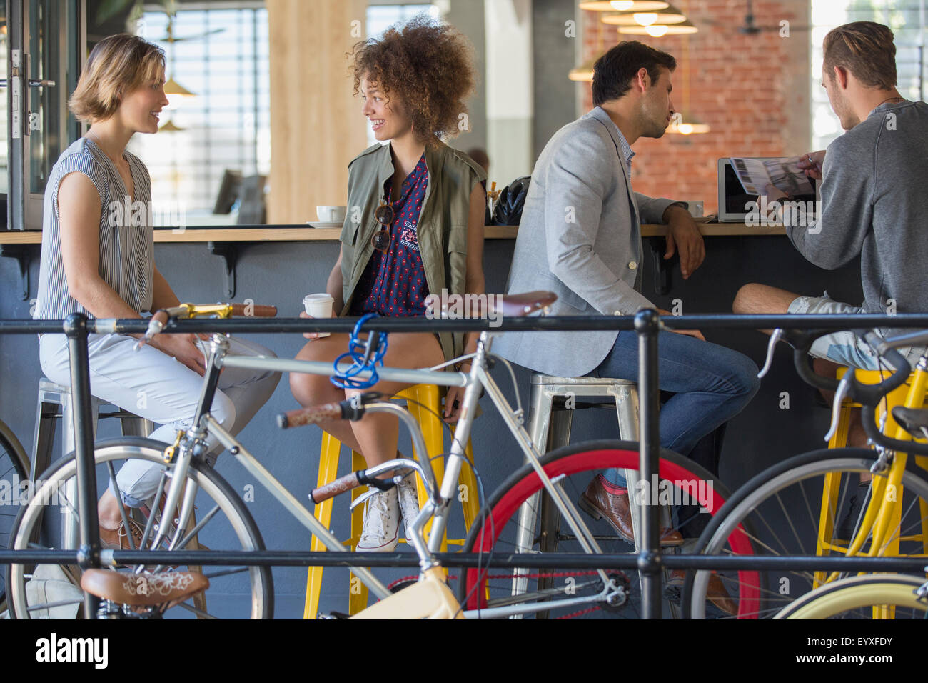 Amici appendere fuori a parlare e a bere caffè al patio con biciclette Foto Stock