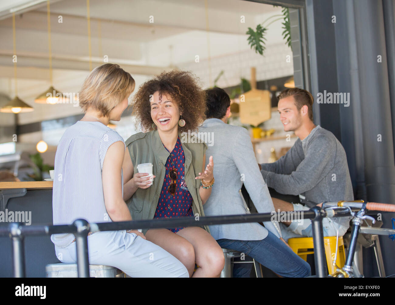 Ridere amici appendere fuori a bere caffè sul patio cafe Foto Stock