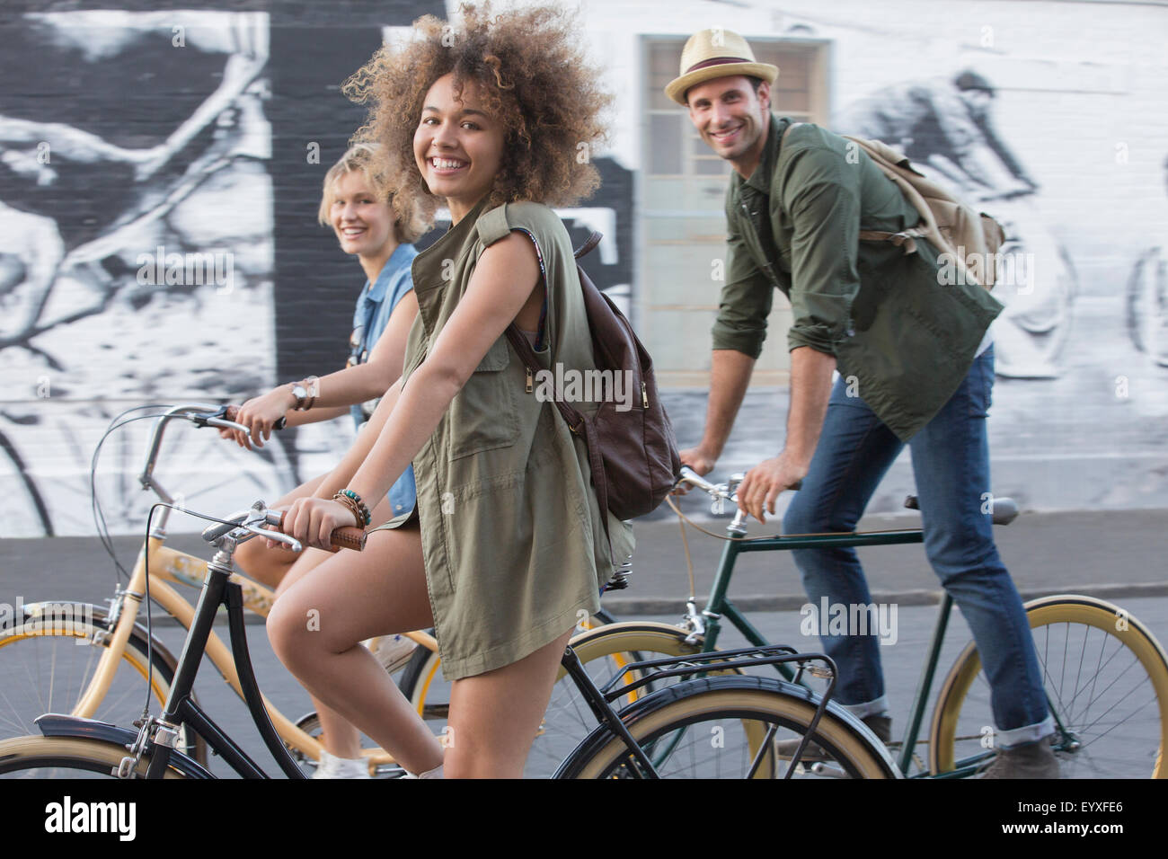 Ritratto sorridente amici equitazione biciclette su strada urbana Foto Stock