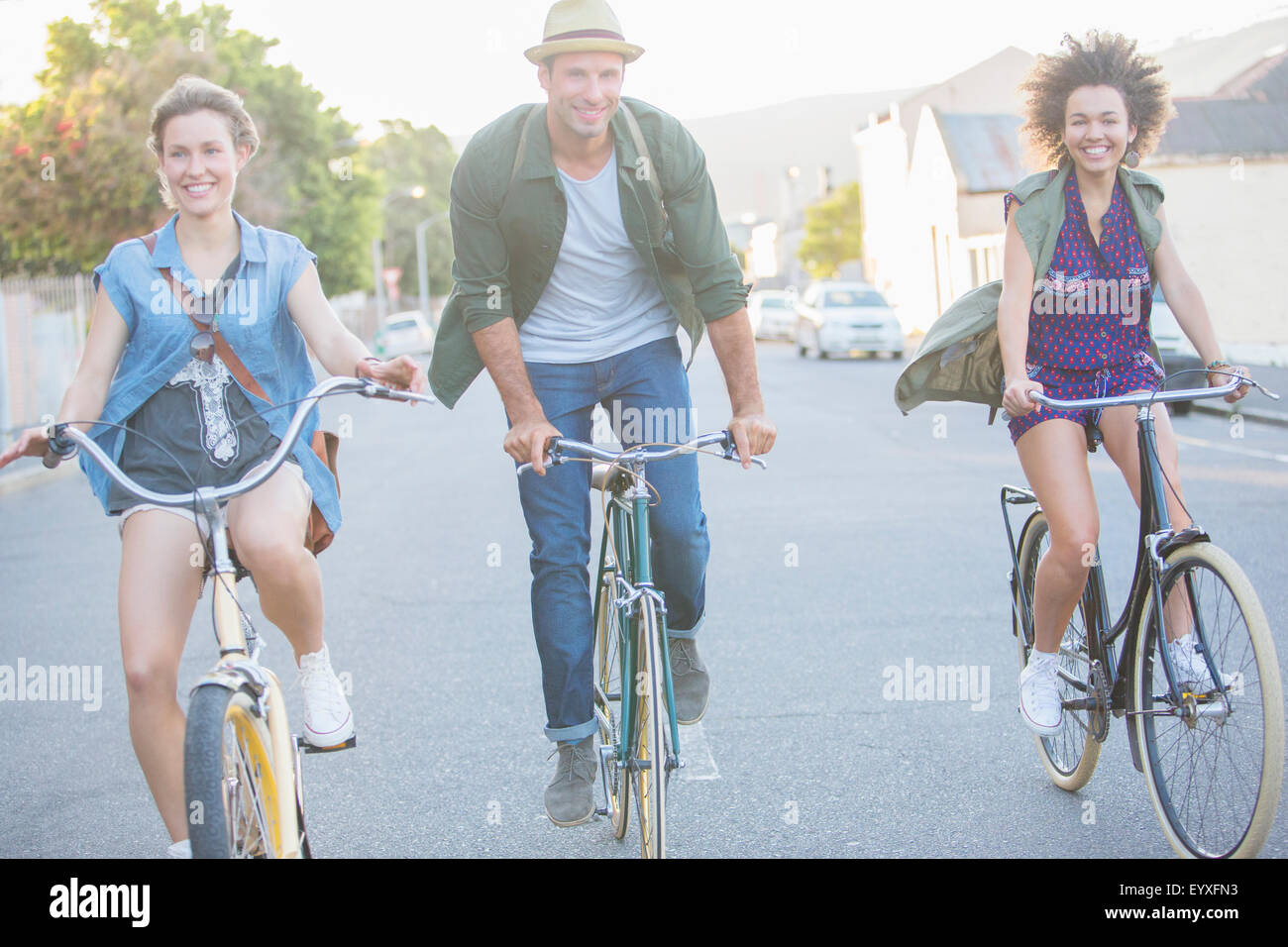 Sorridente amici equitazione biciclette su strada Foto Stock