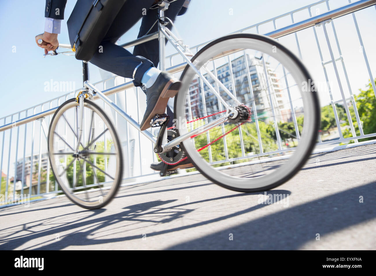 Sezione bassa imprenditore della tuta Bicicletta Equitazione sulla soleggiata marciapiede urbano Foto Stock