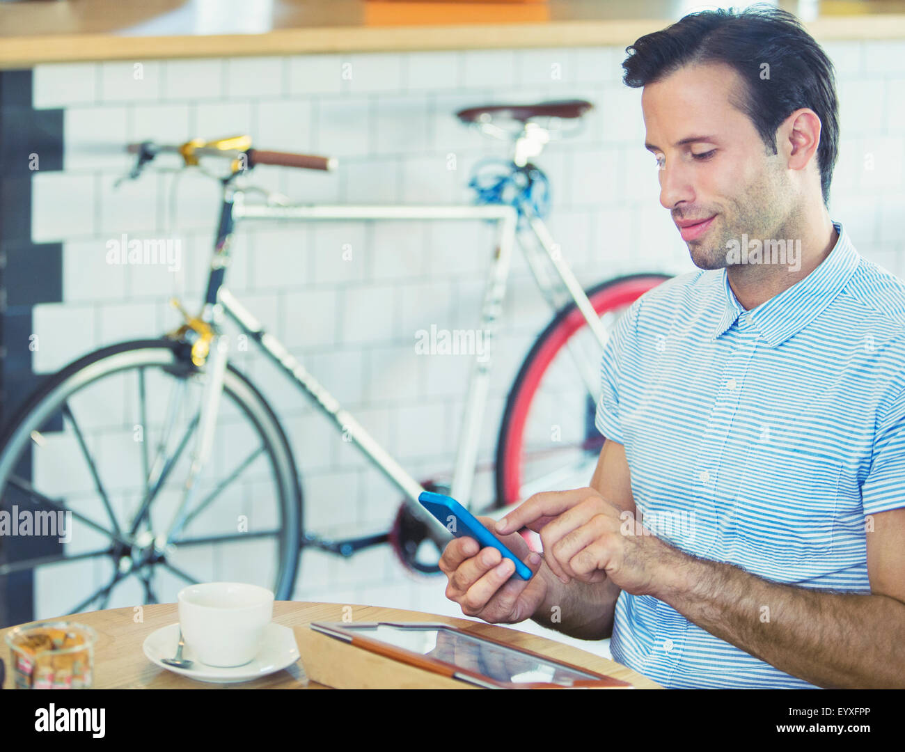 L'uomo gli sms con il telefono cellulare vicino a bicicletta in cafe Foto Stock