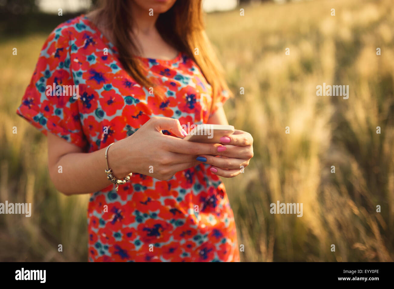 Giovane donna close-up in abito rosso utilizzando mobile smart phone, esterna di estate Foto Stock