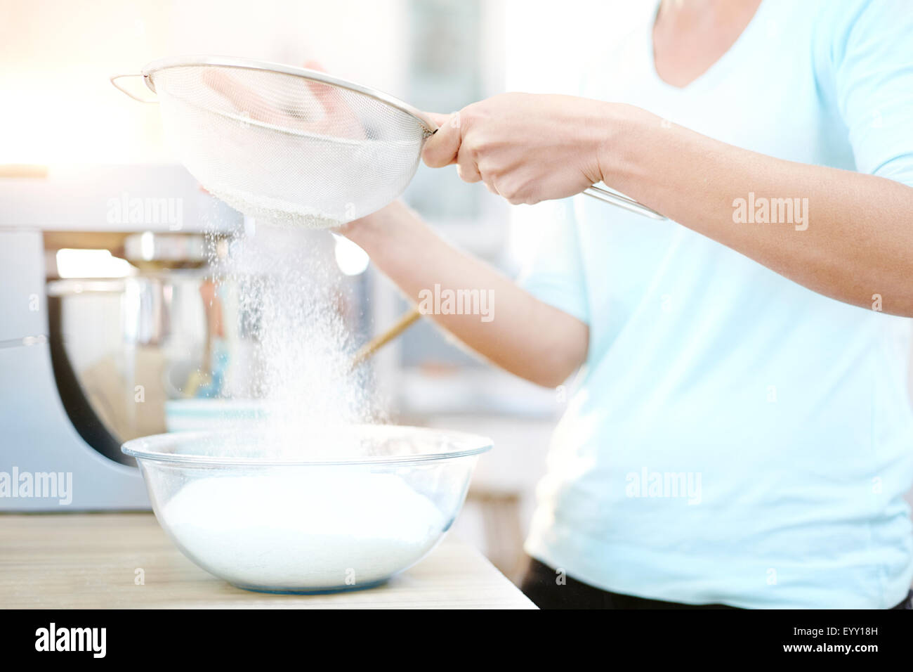 Donna setacciare la farina e il lievito in cucina Foto Stock
