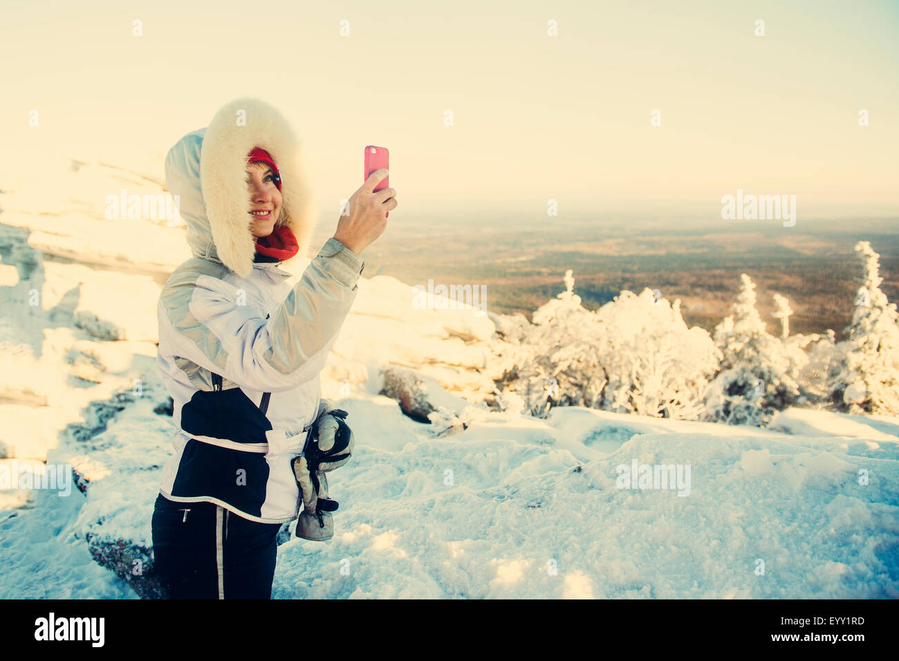 Escursionista caucasica tenendo cellulare fotografia nella neve Foto Stock