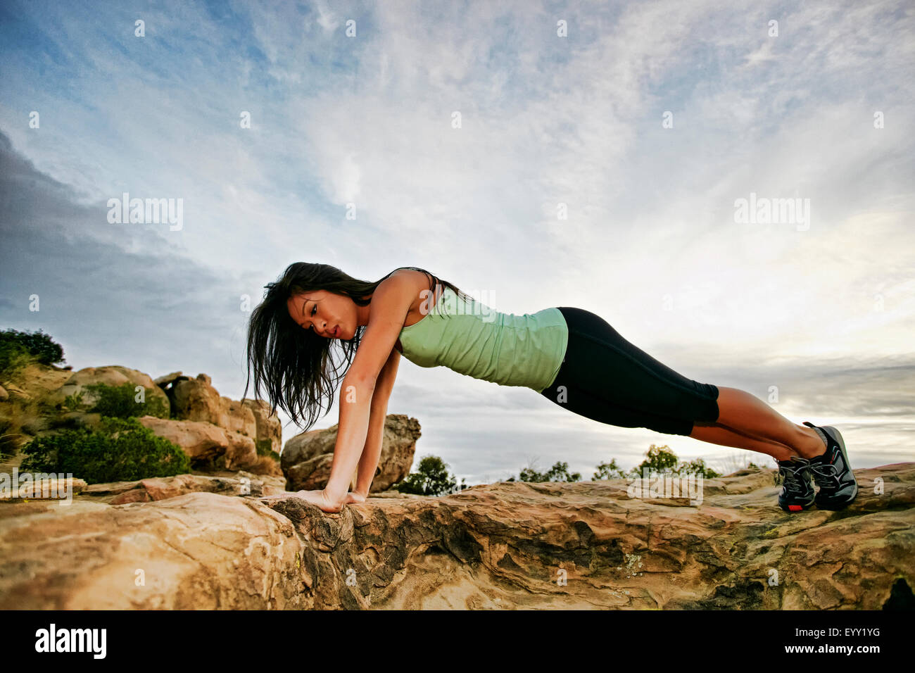 Donna vietnamita facendo push-up sulla collina rocciosa Foto Stock