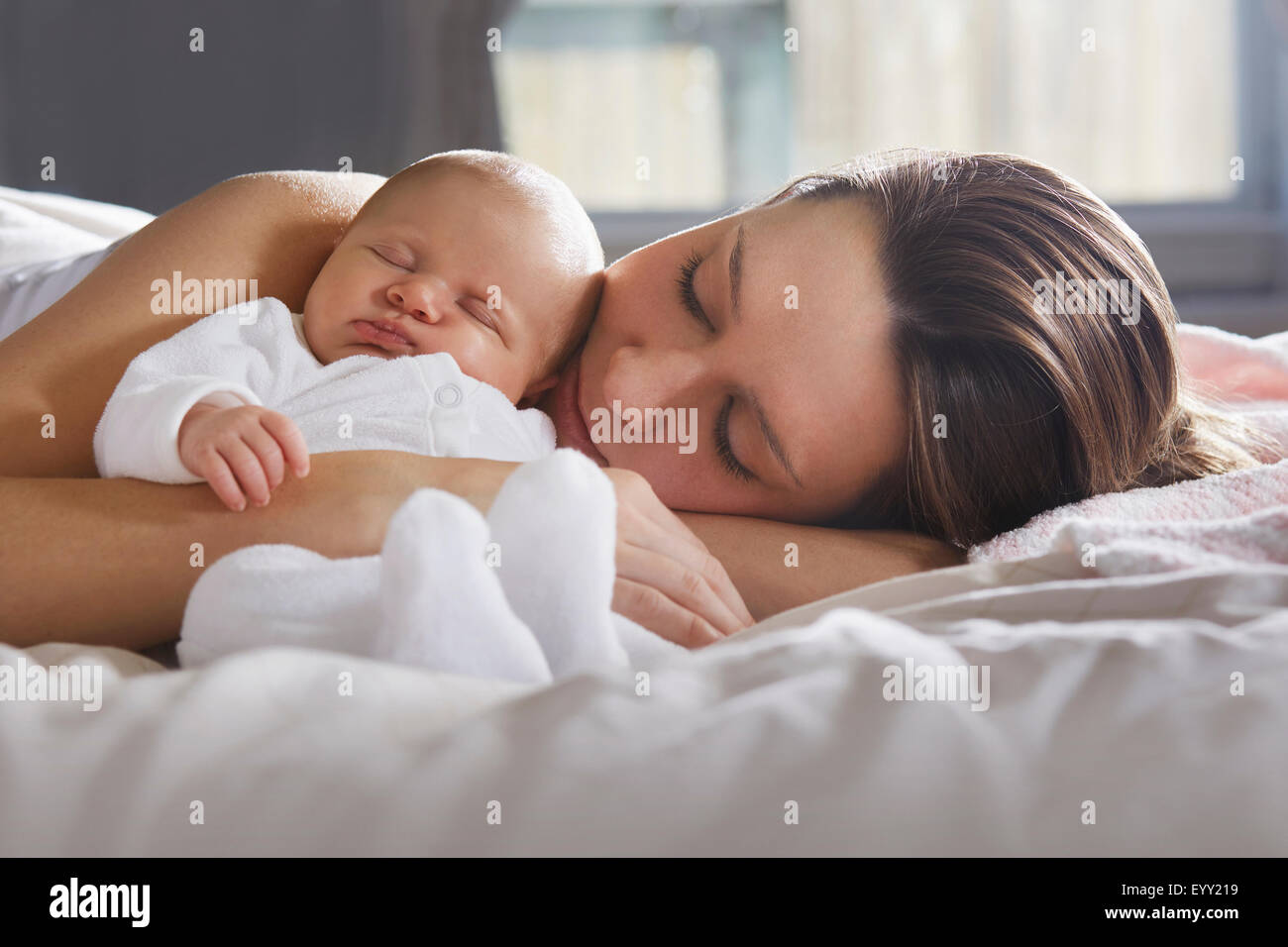 Madre abbracciando neonato sul letto Foto Stock