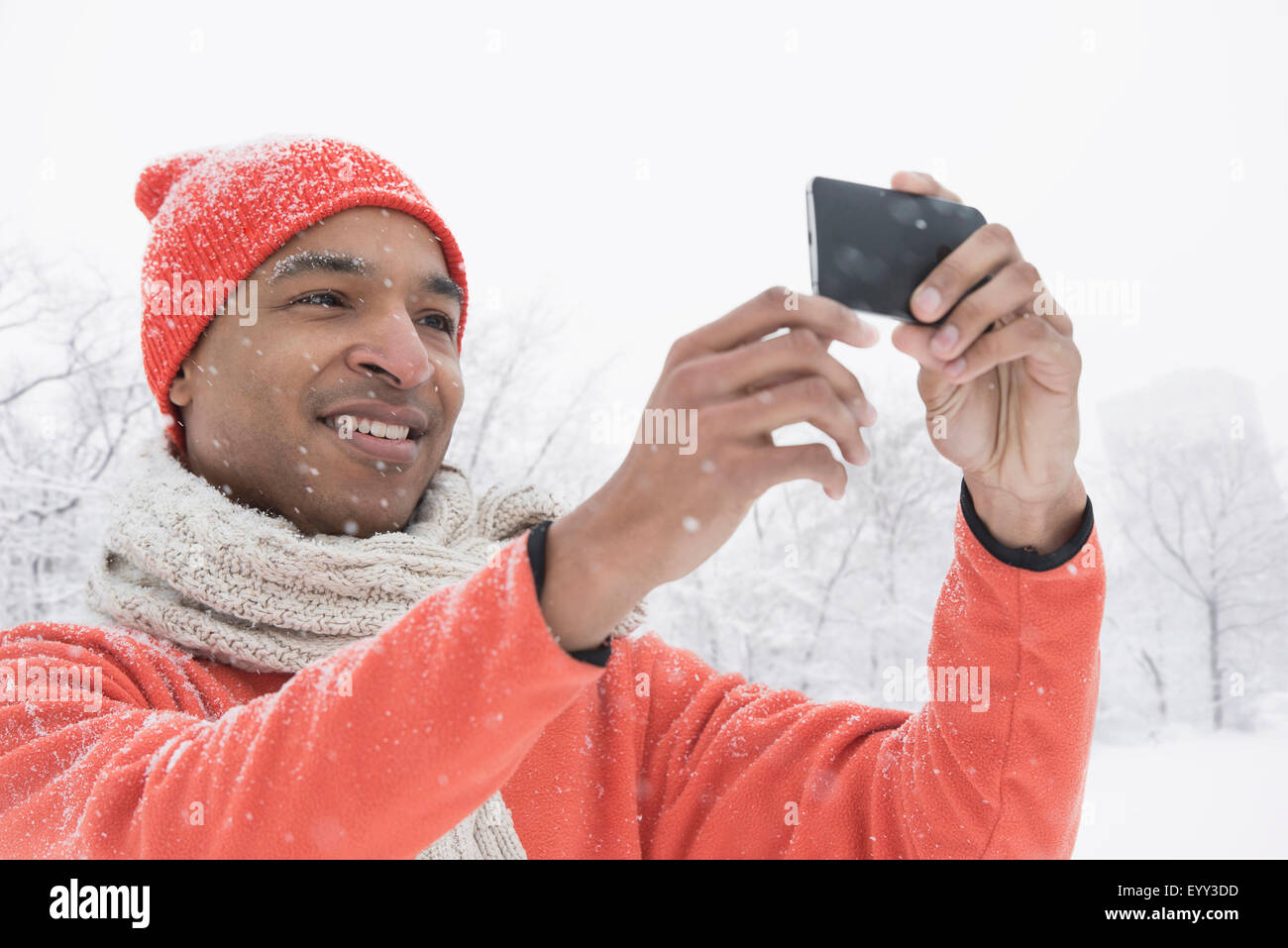 Uomo nero utilizzando il cellulare in neve Foto Stock