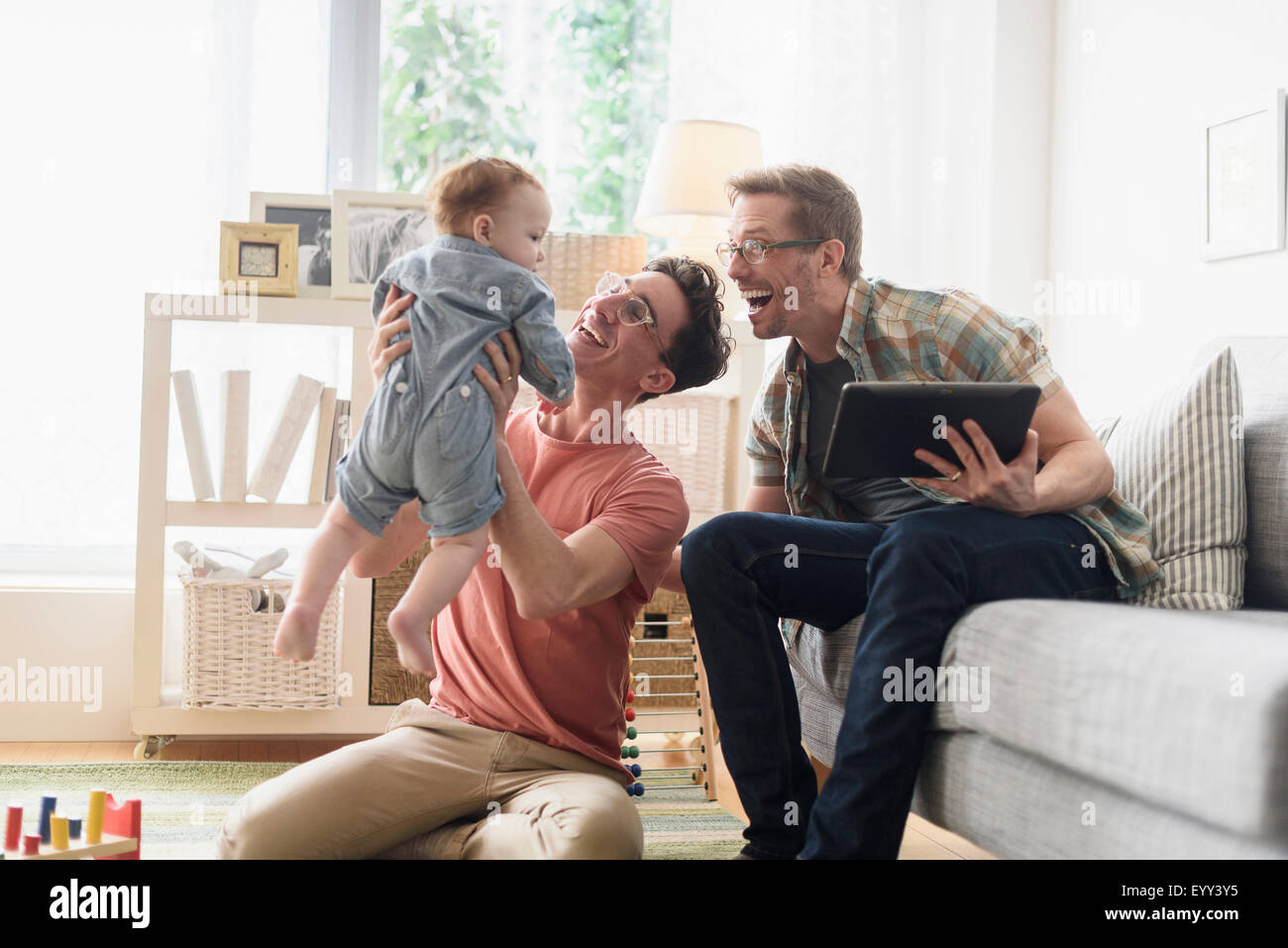 Caucasica padri gay e baby rilassante nella stanza vivente Foto Stock