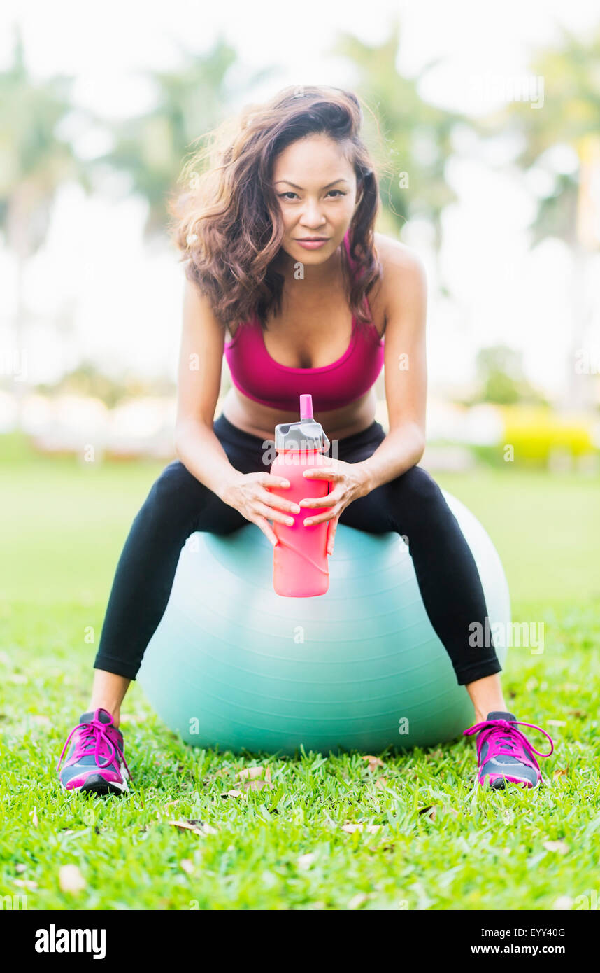 Donna cinese seduto sulla sfera di fitness in posizione di parcheggio Foto Stock