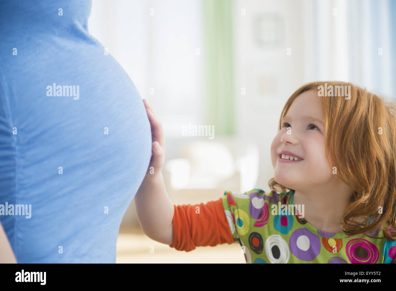 Ragazza caucasica toccando ventre della madre durante la gravidanza Foto Stock