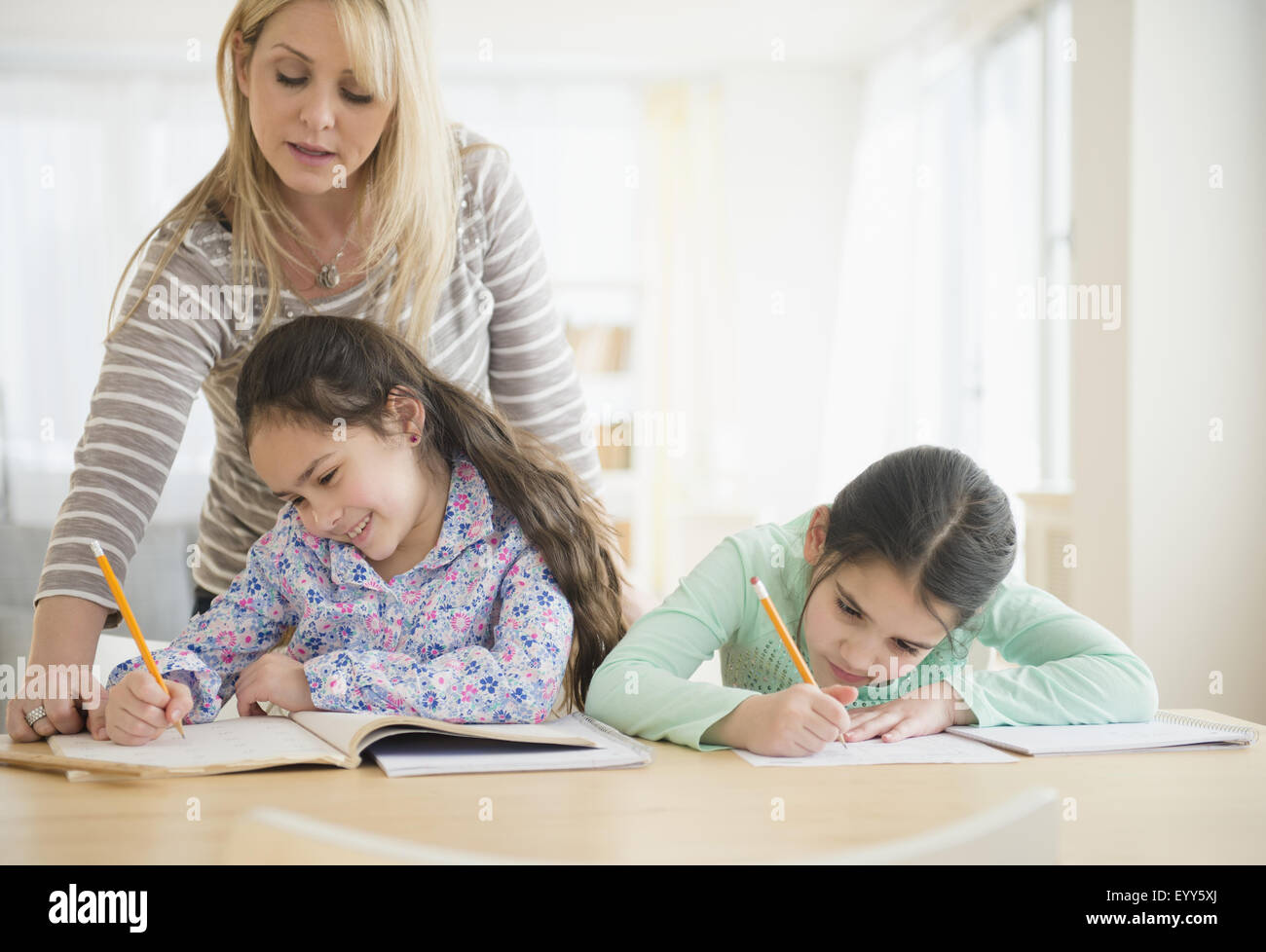 Madre caucasica aiutando le figlie fare i compiti Foto Stock