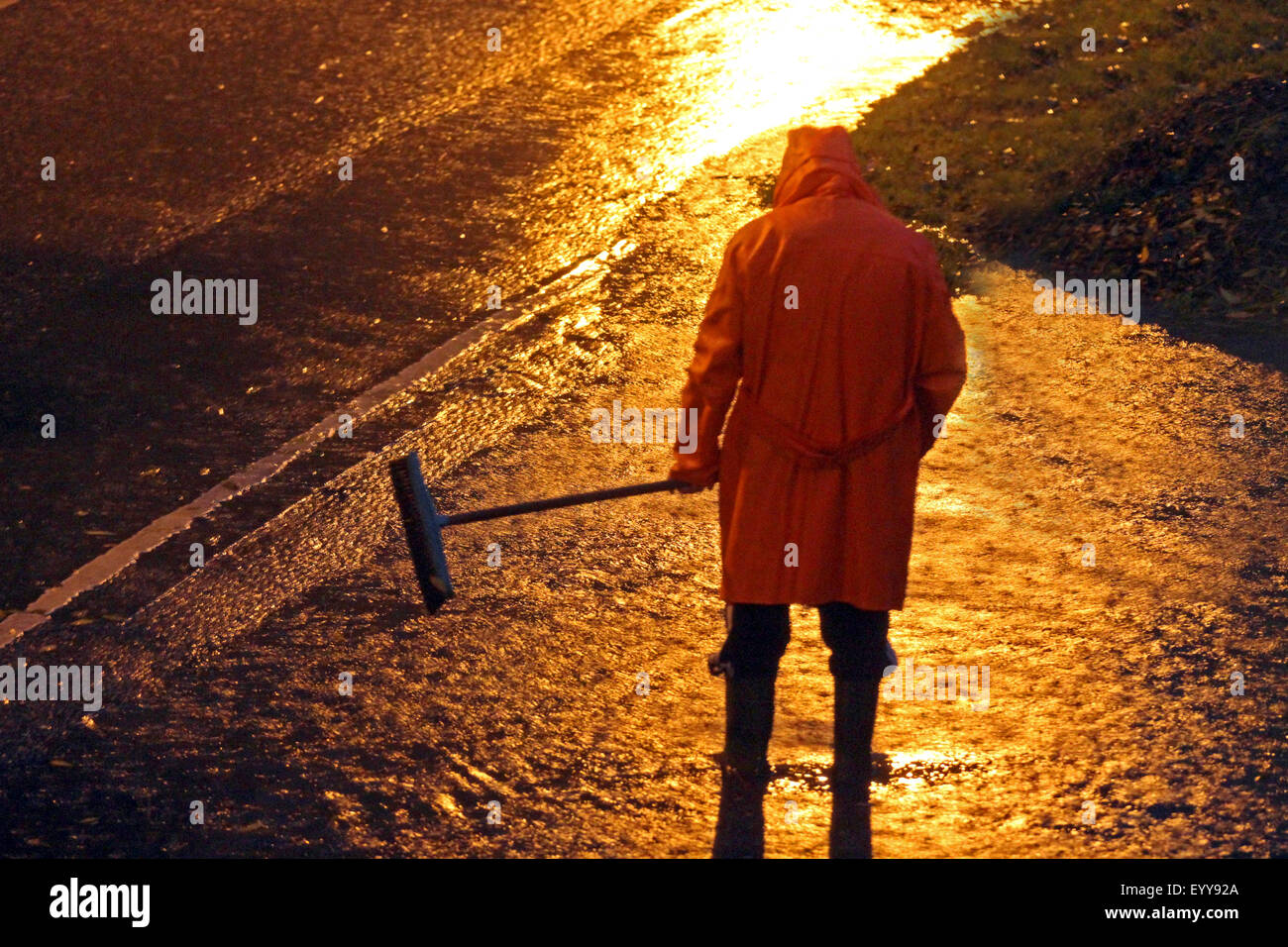 Uomo che pulisce il drenaggio di acqua con una scopa, Germania Foto Stock