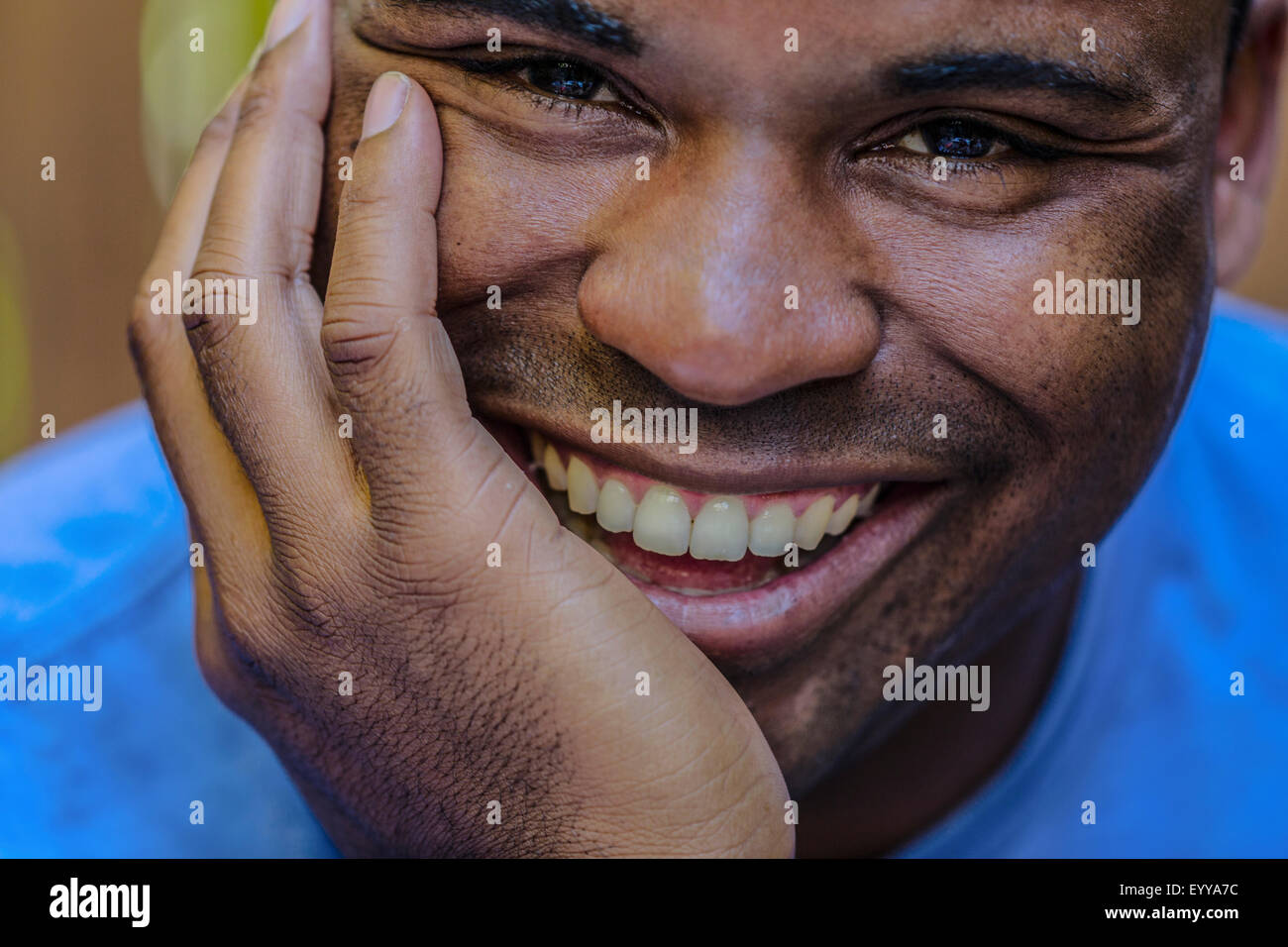 Close up di sorridere uomo nero in appoggio mento in mano Foto Stock