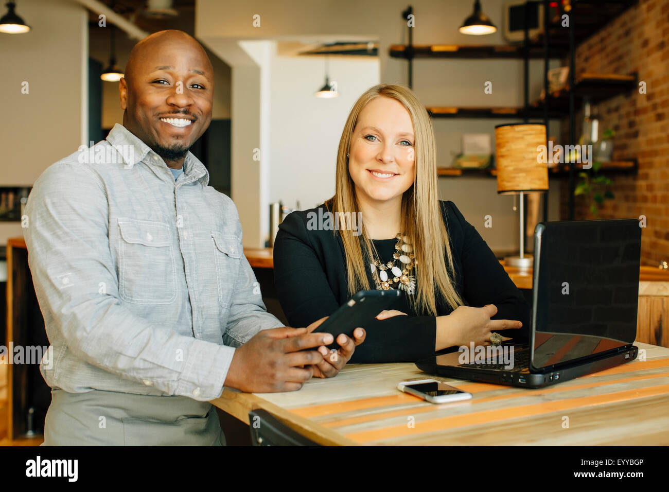Cameriere e imprenditrice utilizzando la tecnologia in cafe Foto Stock