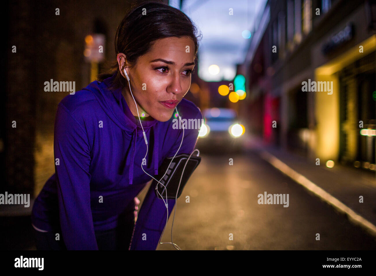 Runner ispanica in appoggio su una strada di città di notte Foto Stock
