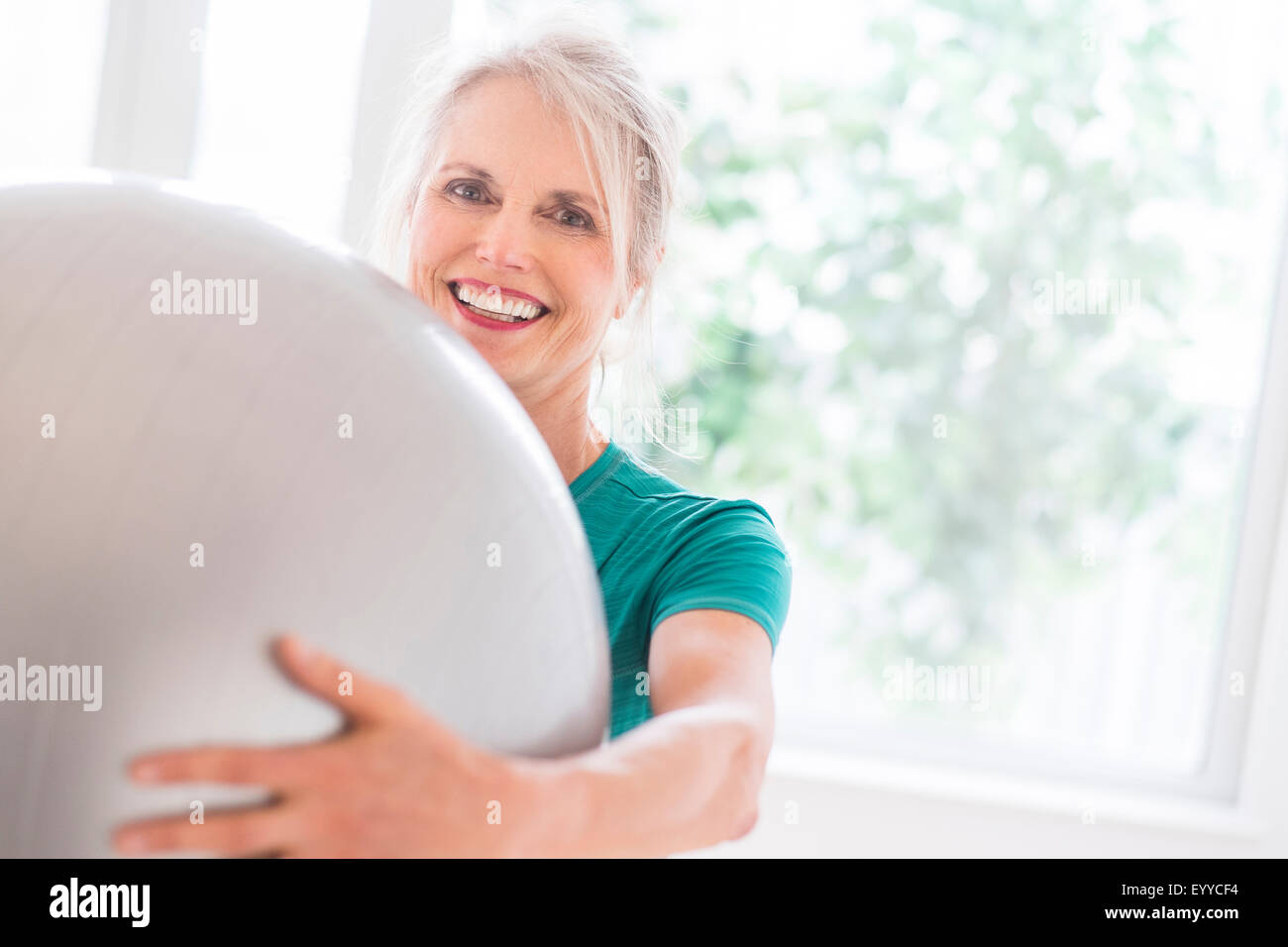 I vecchi donna caucasica tenendo palla ginnica in palestra Foto Stock