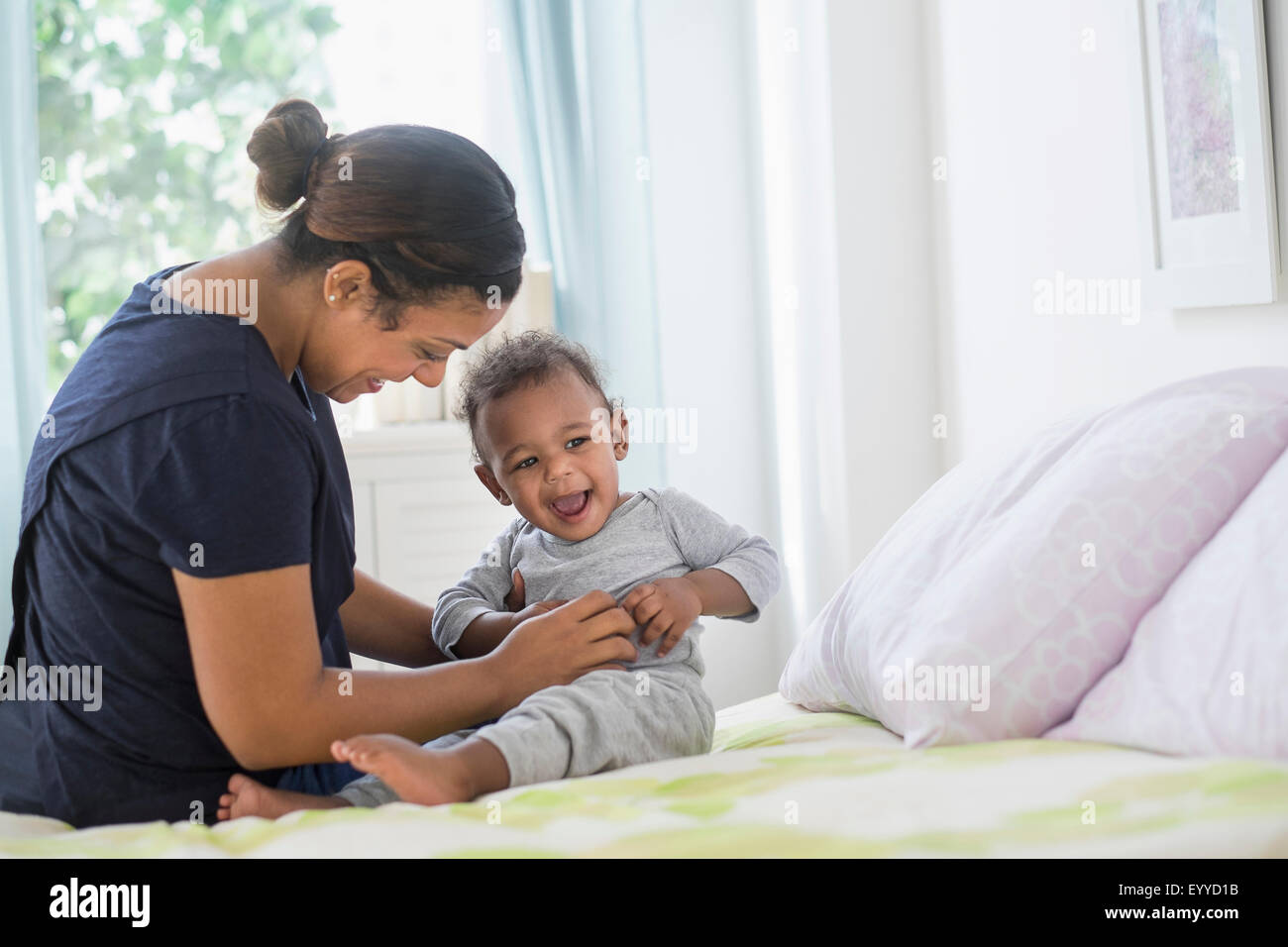 Razza mista madre solletico baby figlio sul letto Foto Stock