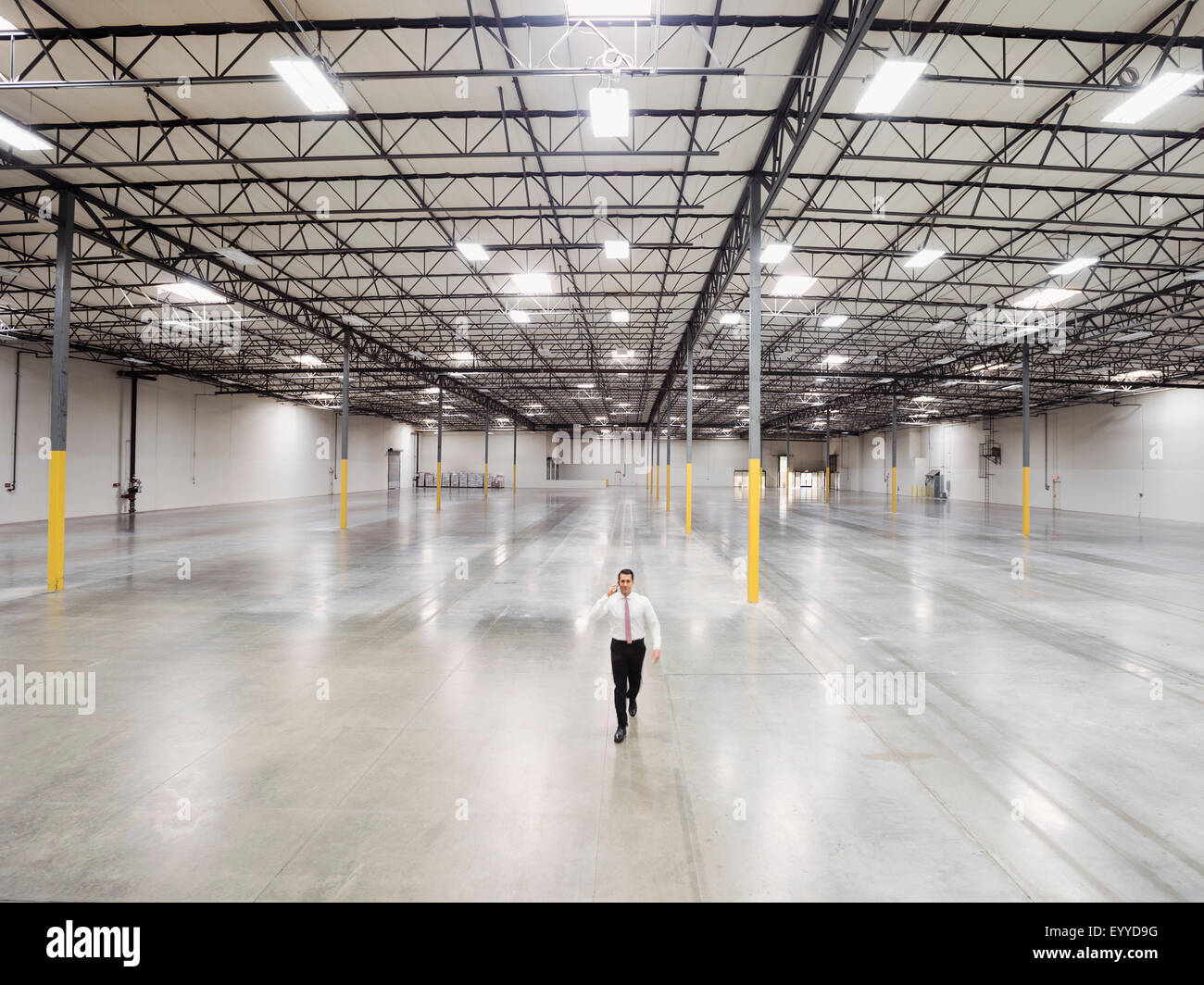 Imprenditore caucasico camminando in magazzino vuoto Foto Stock