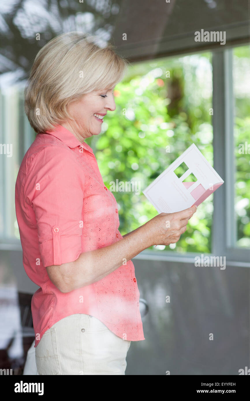 Sorridente donna caucasica la lettura della scheda Foto Stock