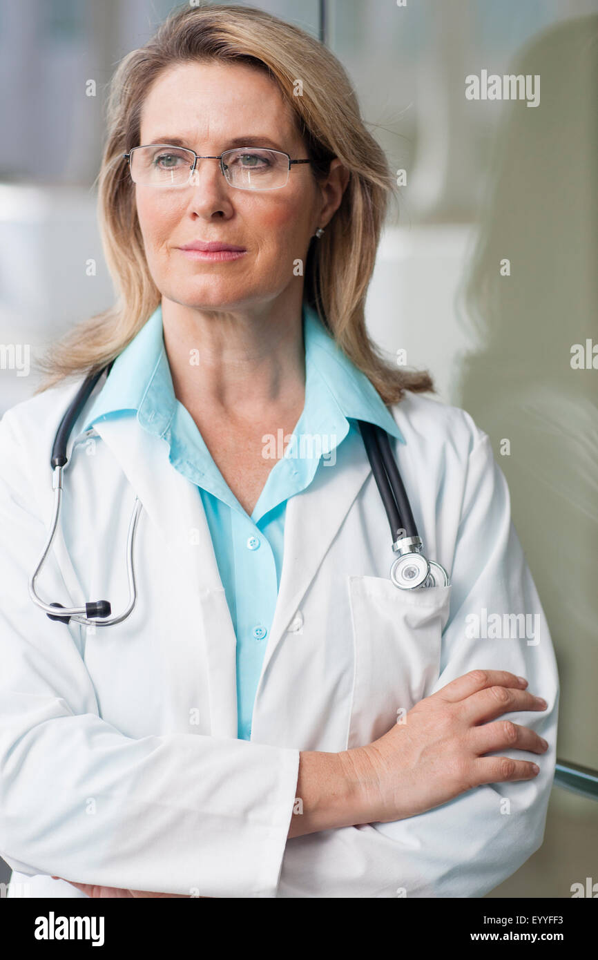 Medico caucasici in piedi con le braccia incrociate Foto Stock