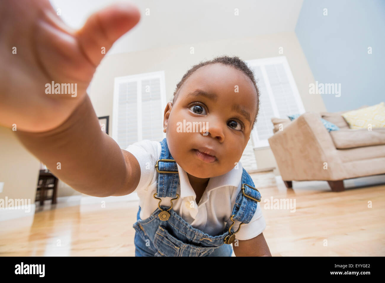 Black baby raggiungendo per la fotocamera su camera soggiorno piano Foto Stock