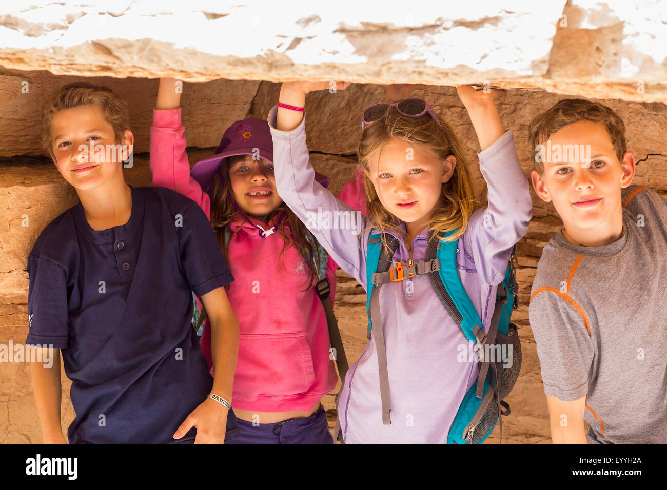 I bambini accovacciati sotto formazione di roccia Foto Stock