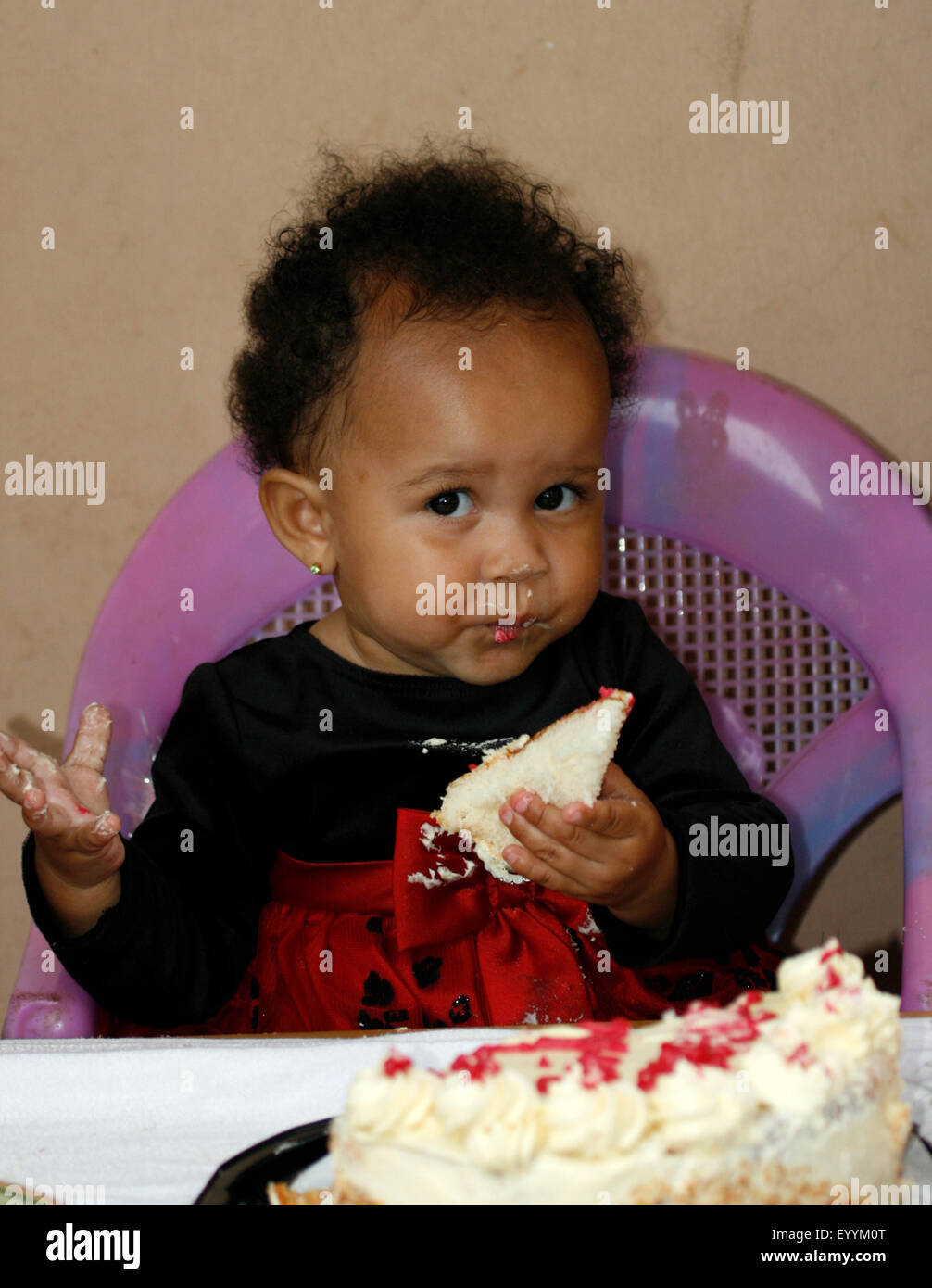 Un bambino di mangiare la sua torta come lei festeggia il suo primo compleanno Foto Stock