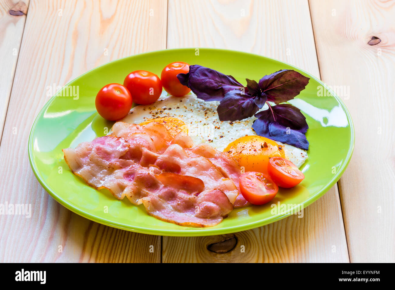 Stuzzicante uova fritte con pancetta affumicata su una lastra decorata magnificamente Foto Stock