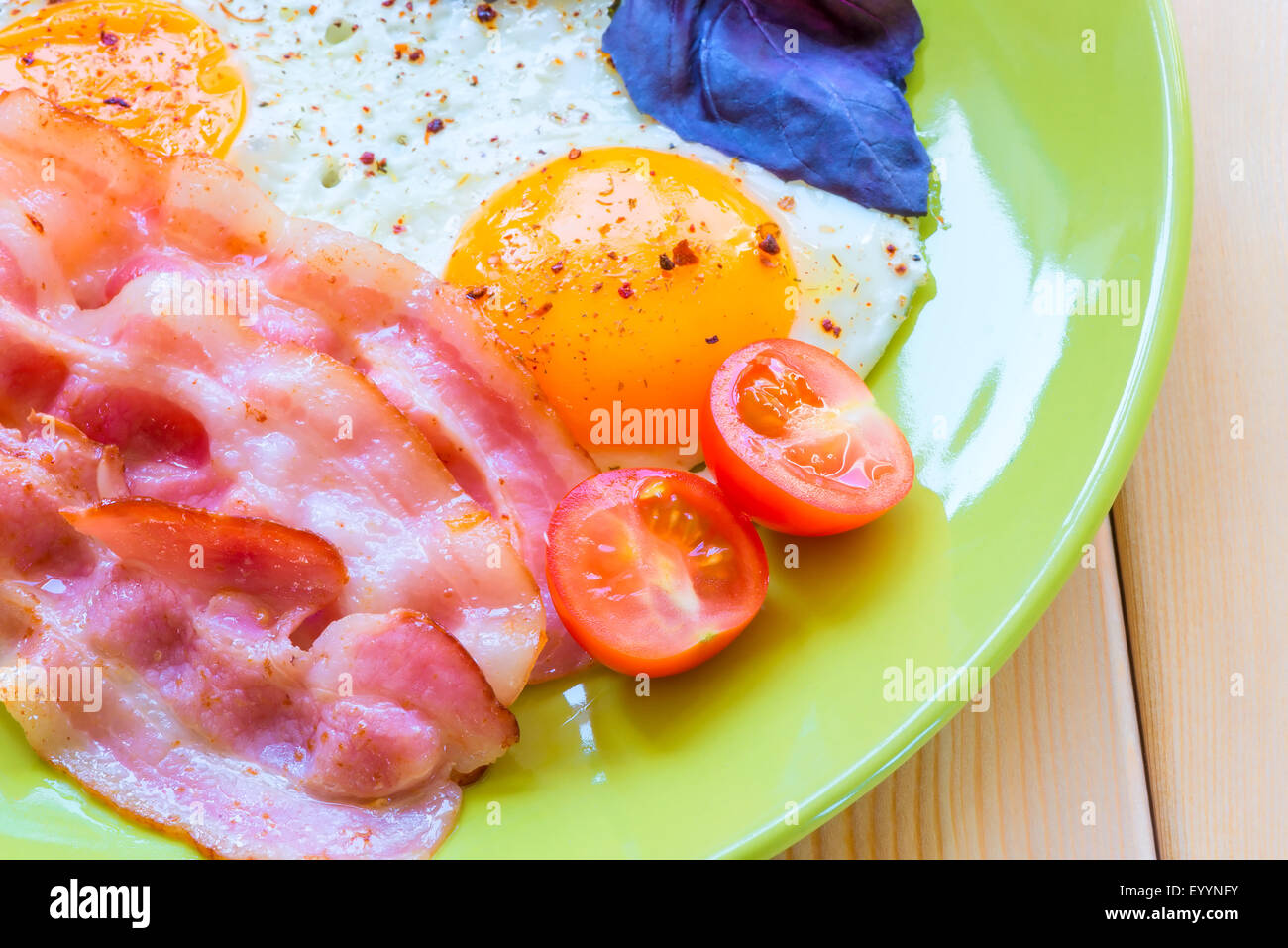 Uova fritte con pancetta close-up su una piastra verde Foto Stock
