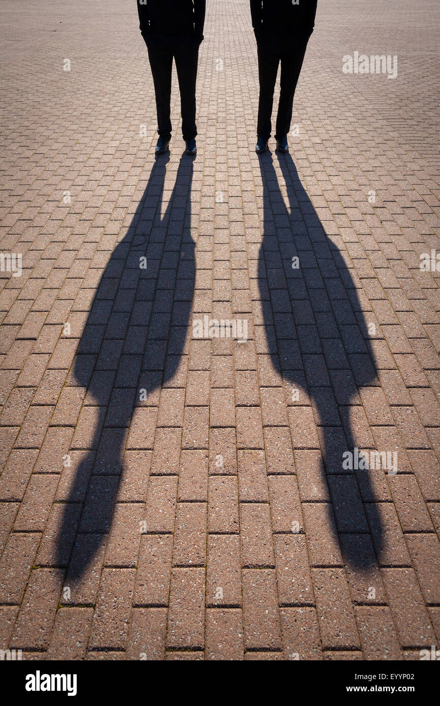 Le ombre di due persone sulla pavimentazione di blocco Foto Stock