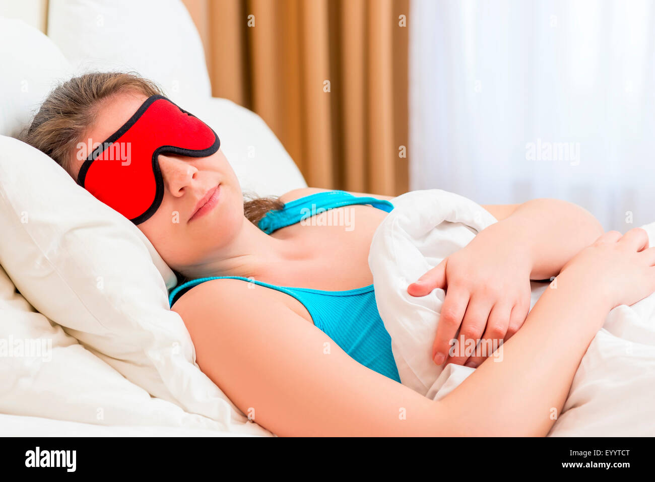 Una donna con occhio maschera dorme sotto una coperta Foto Stock