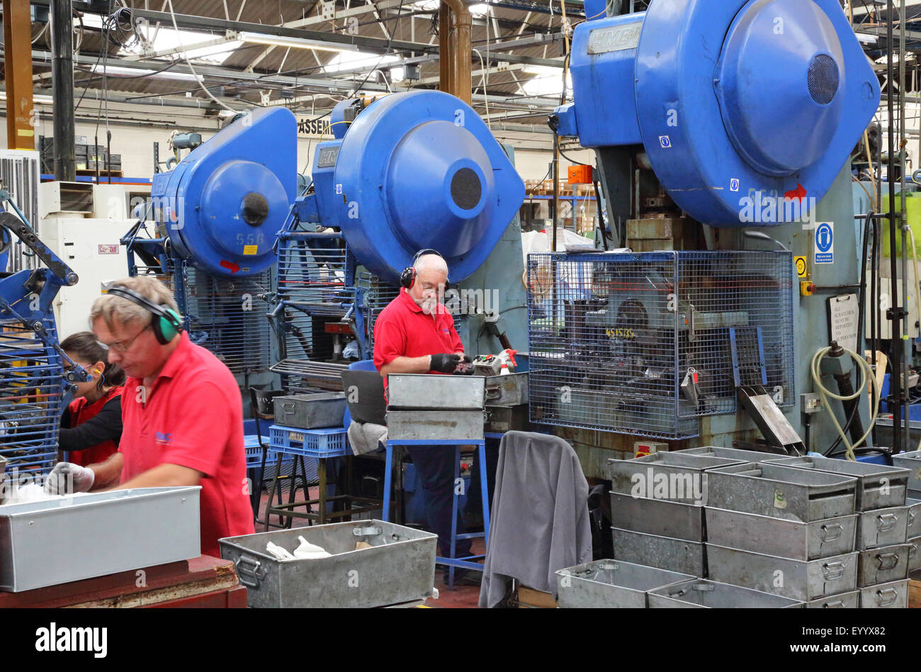 I lavoratori di una fabbrica per la produzione di componenti metallici per l'industria edilizia utilizzando acciaio grande macchine di pressatura Foto Stock